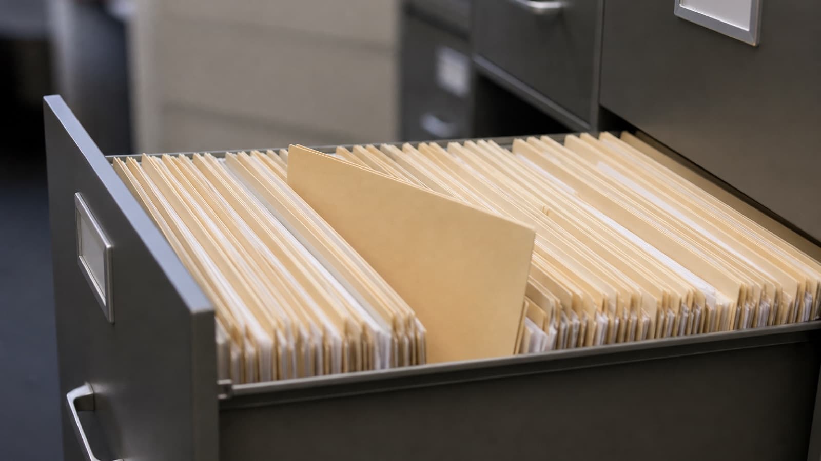An open filing cabinet drawer packed with manila medical record folders, illustrating RADV record retrieval workloads